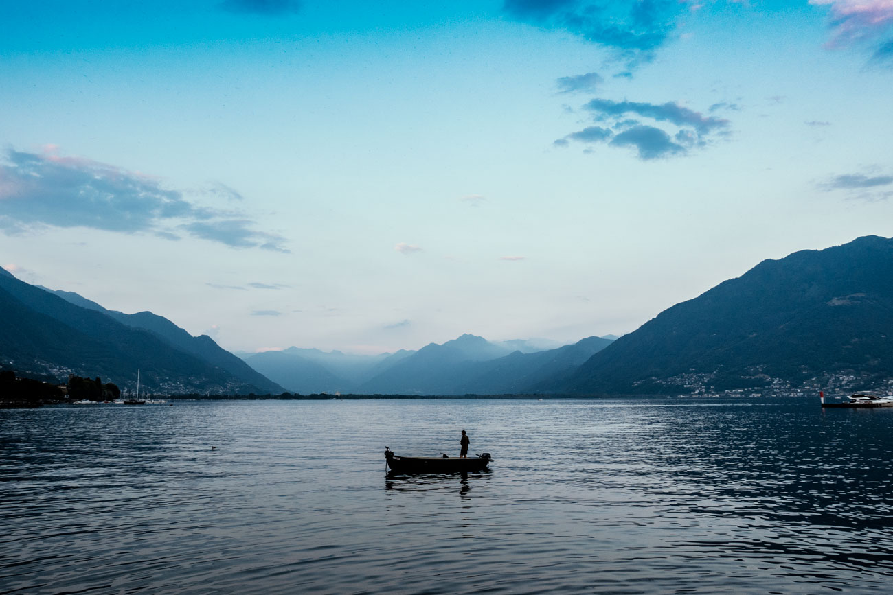 Blick auf den Lago Maggiore am frühen Abend. Ein Boot ist in der Mitte des Sees