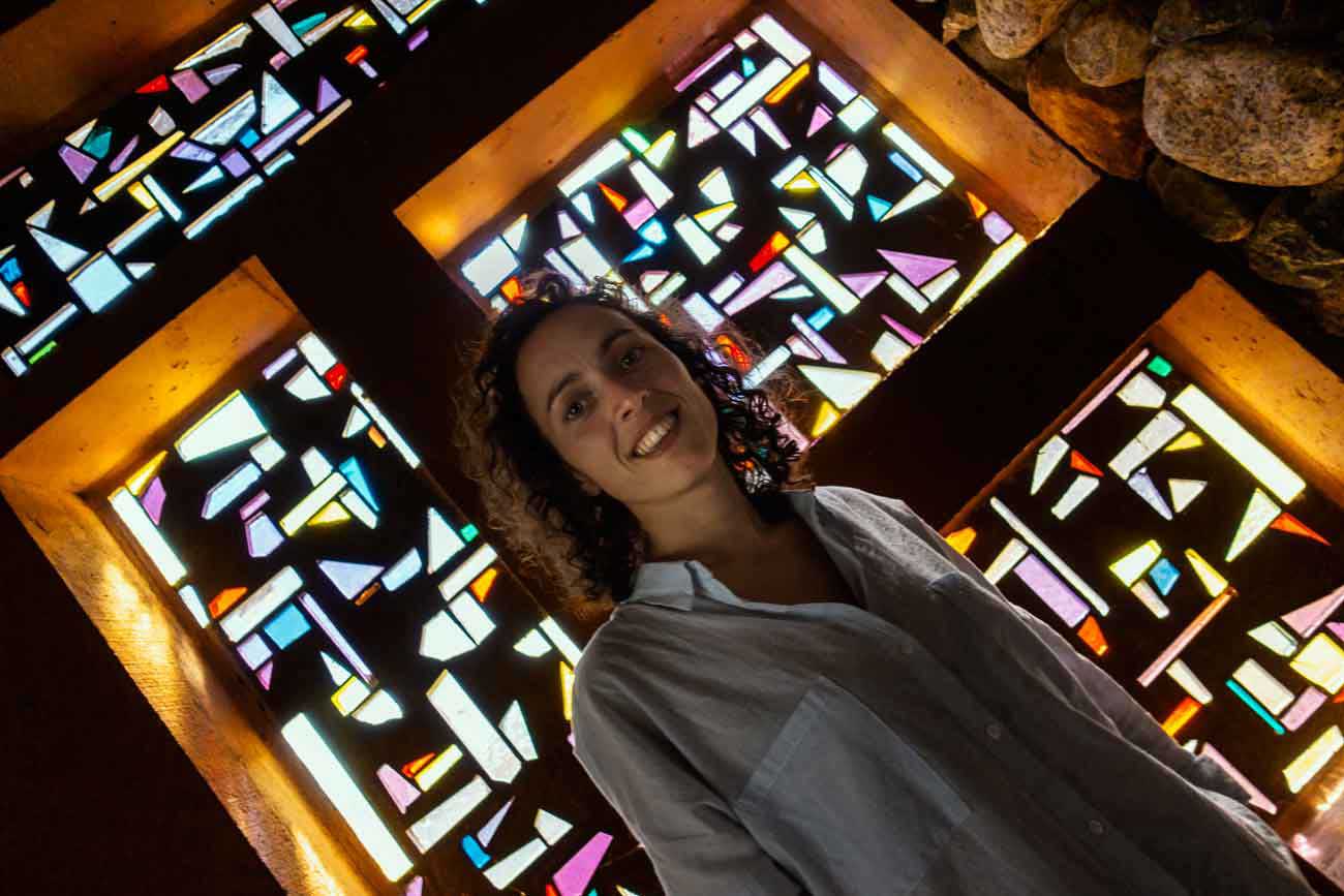 Auf dem Grimsel Pass gibt es außerdem eine kleine Kapelle mit Mosaikfenstern. Eine Frau steht vor einem diesem Fenster und lächelt